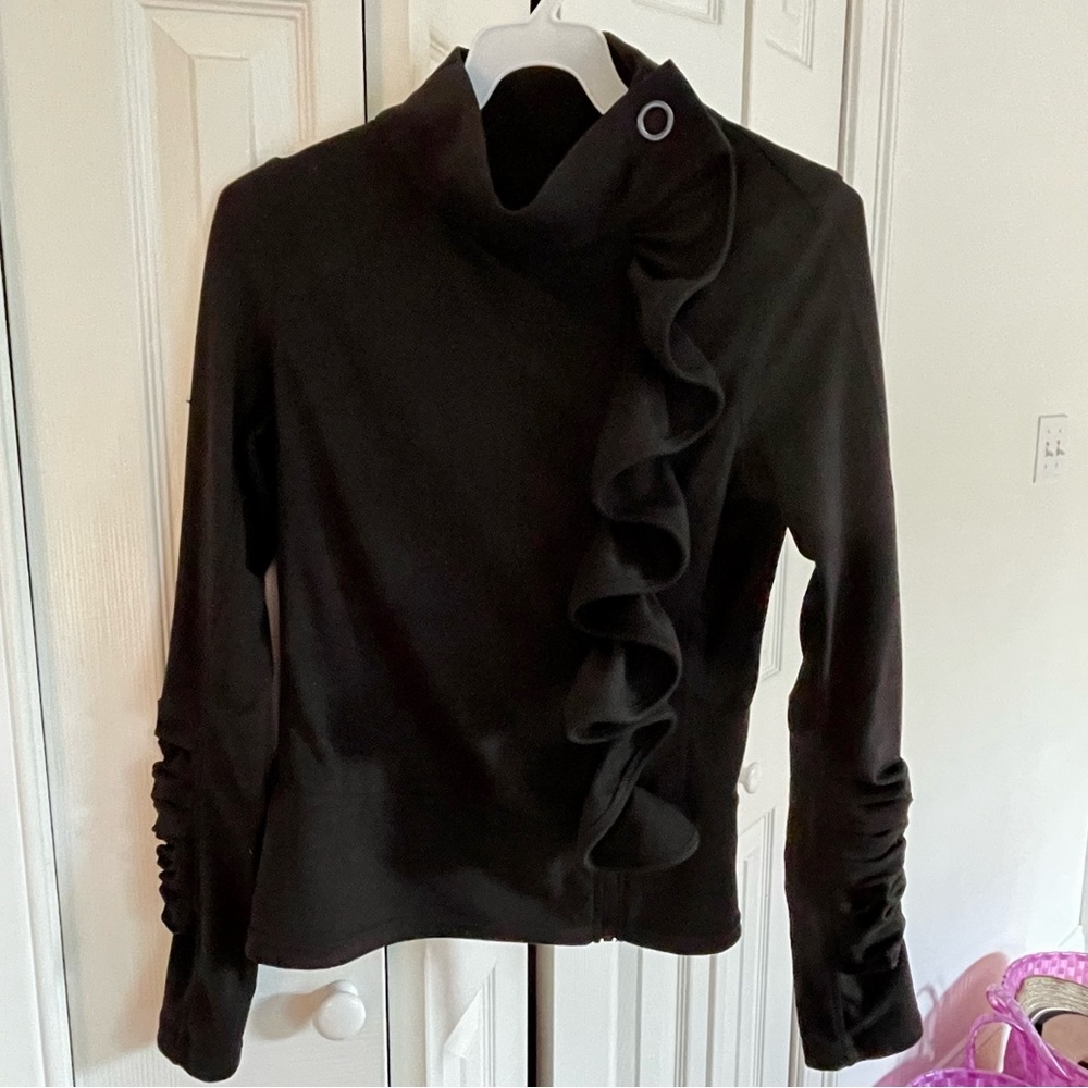 Stylish black athletic jacket with ruffle, zipper, and button detail.